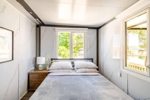 a large white bedroom with a bed and two windows at Overlooking a Park - A sunny escape in Rooty Hill