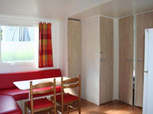 Mobil home pour 8 avec terrasse à Payrac - API-1-52-1222 في Payrac: غرفة بها طاولة حمراء وكراسي ونافذة