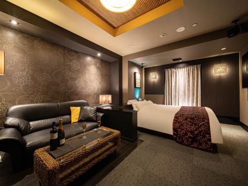 a hotel room with a bed and a couch at Hotel PENTHOUSE Kanayama - Adult Only in Nagoya