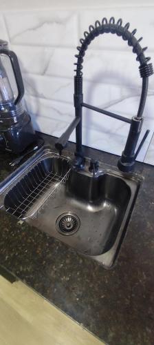 a kitchen sink with a black hose over it at Casa Brisa ar condicionado excelente banho a gás e acabamento premium próximo ao mar in Imbé