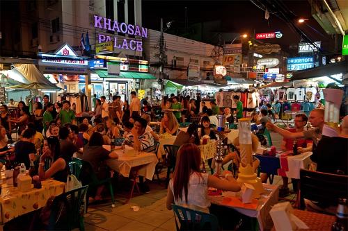 a crowd of people sitting at tables in a street at night at zNAP - Khaosan Road สแนป ตรอกข้าวสาร in Bang Bua Thong Railway Station