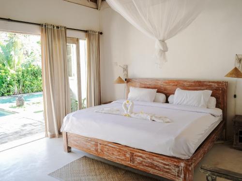 Un dormitorio con una cama con cabecero de madera. en Damai Villa Uluwatu - 4 Rooms with pool near Thomas Beach, en Uluwatu