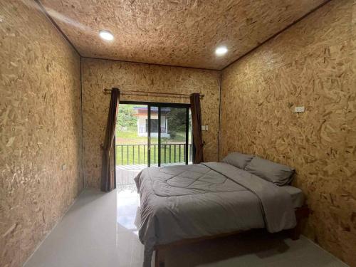 a bedroom with a bed in a room with a window at Grand Bungalow in Ban Ting Rai