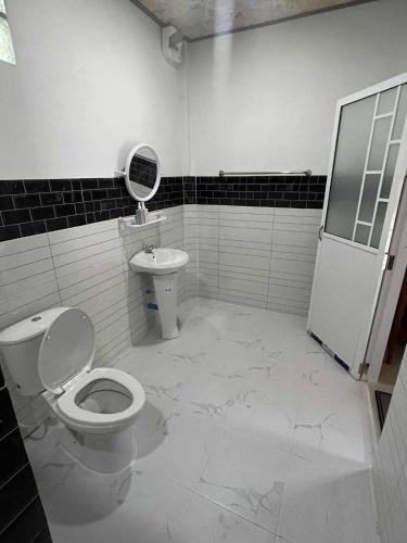 a white bathroom with a toilet and a sink at Grand Bungalow in Ban Ting Rai