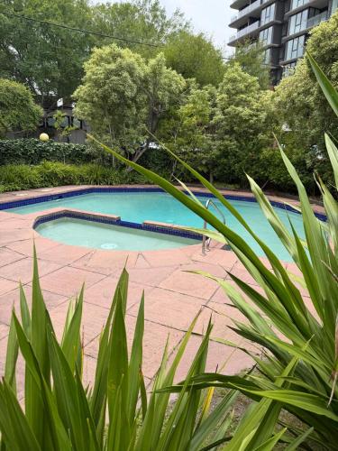 a swimming pool in the middle of a garden at 2 bedroom Art Deco Apartment in Melbourne
