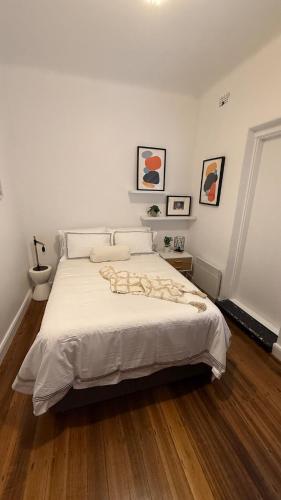 a bedroom with a white bed with a wooden floor at 2 bedroom Art Deco Apartment in Melbourne