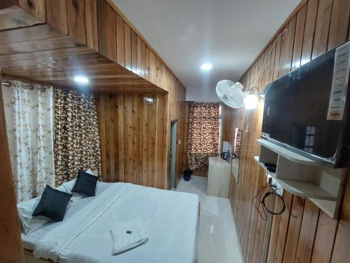 Un dormitorio con una cama y un televisor de pantalla plana. en Hotel Rashak, en Gangtok
