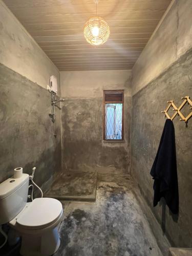 een badkamer met een toilet en een raam bij Into The Blue - Beach House in Unakuruwa