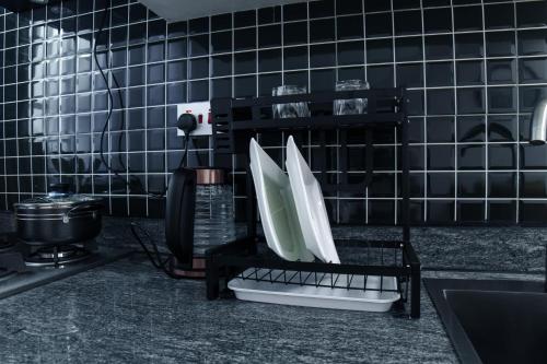a kitchen with black tiled walls and a sink at Lavista Place in Jinja