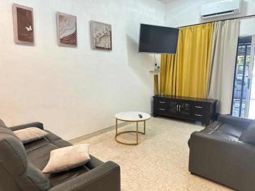 ein Wohnzimmer mit zwei Sofas und einem Flachbildfernseher in der Unterkunft 3 Bedrooms Single Storey Terrace at Taman Inderawasih ,12mins to Penang Bridge , 5mins to Sunway Carnival Mall in Butterworth