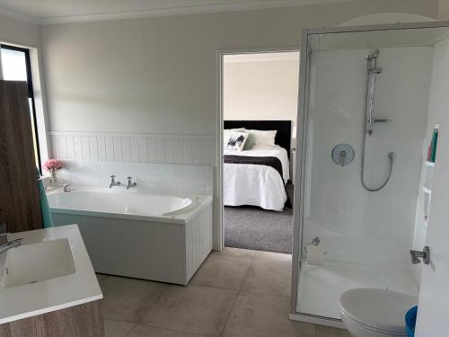 a bathroom with a bath tub and a bed at Just Dean Motueka in Lower Moutere
