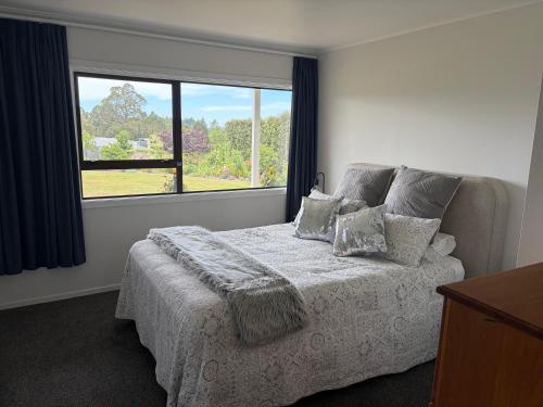 a bedroom with a bed and a large window at Just Dean Motueka in Lower Moutere