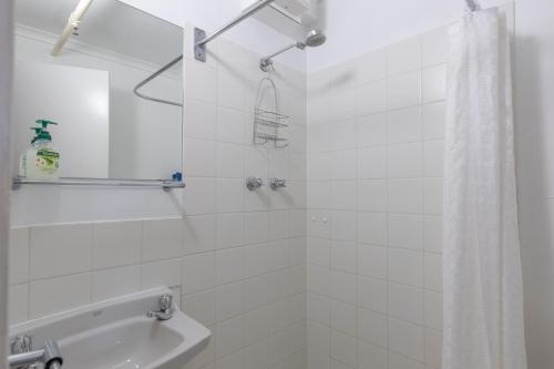 a white bathroom with a shower and a sink at Schuss Alpine Club, Falls Creek in Falls Creek
