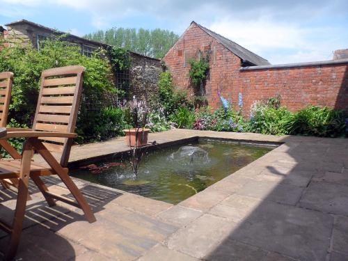 a garden with a pond with two chairs at Littlebridge House in Bromyard