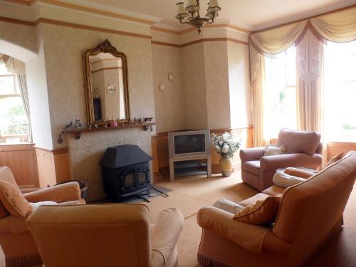 a living room with couches and a fireplace and a television at Littlebridge House in Bromyard