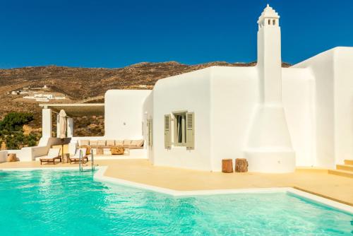 a pool in front of a white building with a lighthouse at Villa Ftelia Boheme in Elia