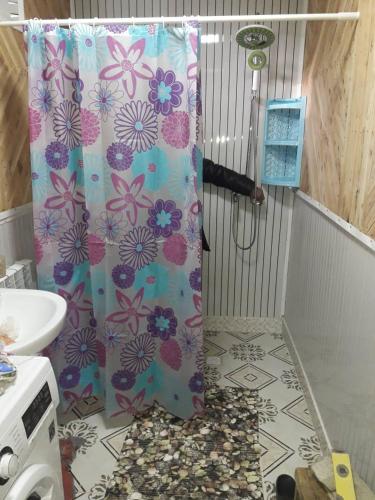a shower curtain with flowers on it in a bathroom at Nurdin Guest House in Kashkaldak