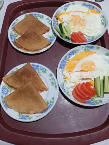 four plates of food on a tray with eggs and vegetables at Nurdin Guest House in Kashkaldak