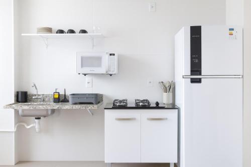 a white kitchen with a refrigerator and a microwave at Ap em condomínio a 500m da Praia com Vista Mar e Vista Praia do Jacaré in Cabedelo