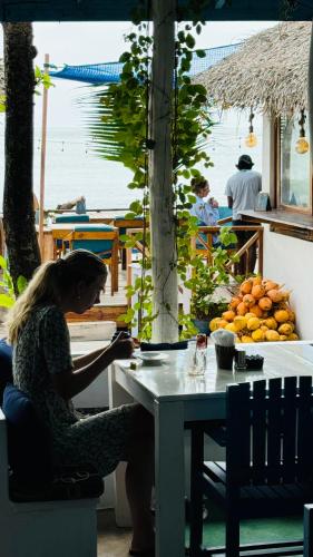 a woman sitting at a table in front of a table with fruit at Hotel Surf Resort in Arugam Bay