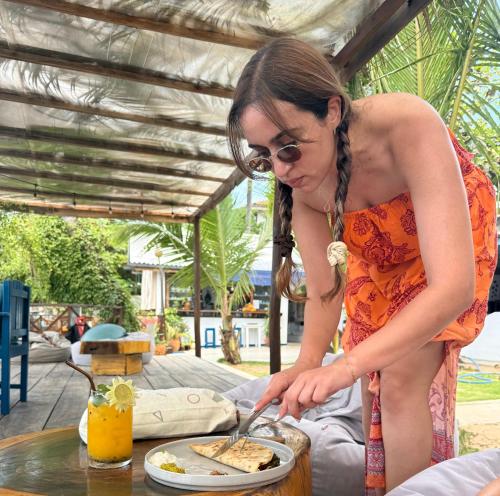 a woman in an orange dress cutting a plate of food at Hotel Surf Resort in Arugam Bay