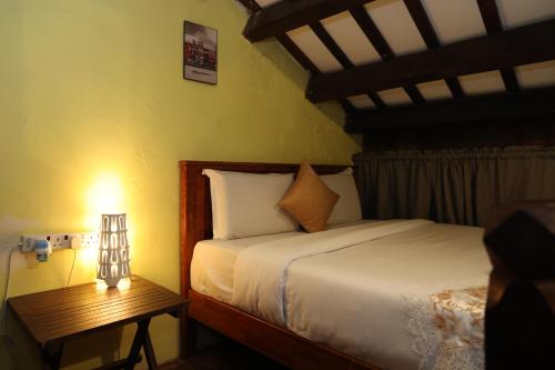 Un dormitorio con una cama y una lámpara sobre una mesa. en The Lang Hoose, en George Town