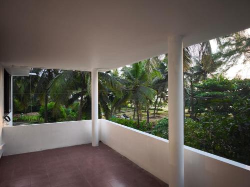 a balcony with white walls and trees and palm trees at Mangalore BeachFront Villa in Mangalore