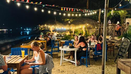 a group of people sitting at tables on the beach at night at Hotel Surf Resort in Arugam Bay