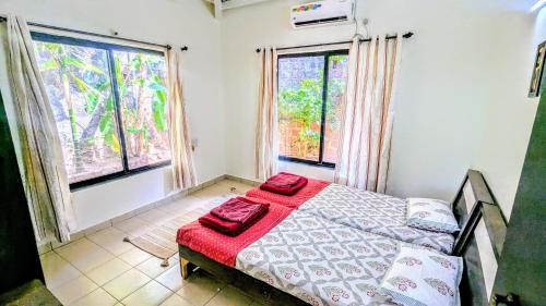 a bedroom with a bed with red sheets and two windows at Redstone Hills, Diveagar in Diveagar