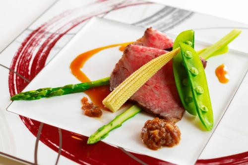 a plate of food with meat and asparagus at La Vista Kusatsu Hills in Kusatsu