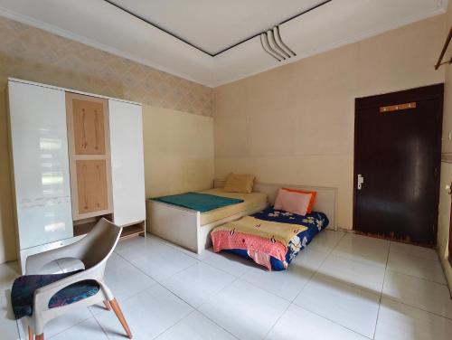 a bedroom with a bed and a chair in it at Chill-Inn near Surabaya Zoo Syariah in Surabaya
