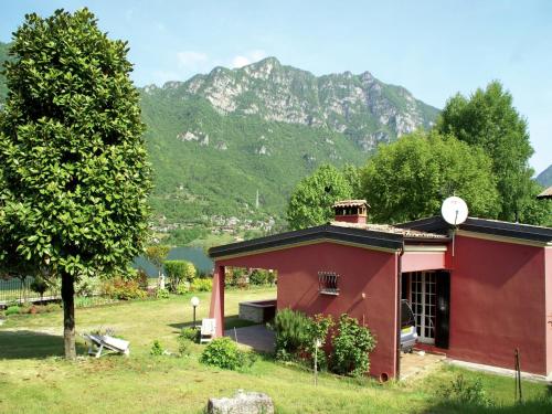 a red house with a tree and mountains in the background at Idyllic cottage next to the beautiful Lake Idro in Crone