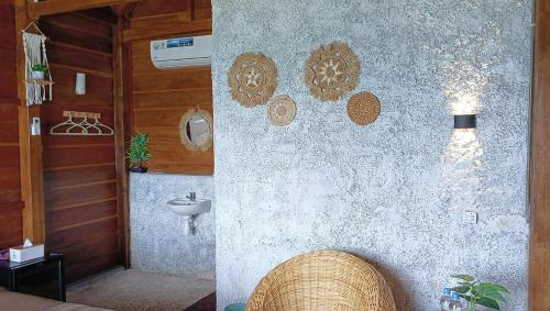 Casablanca Bira Resort في Tabutule: حمام به جدار به حوض غسيل وكرسي من الخيزران