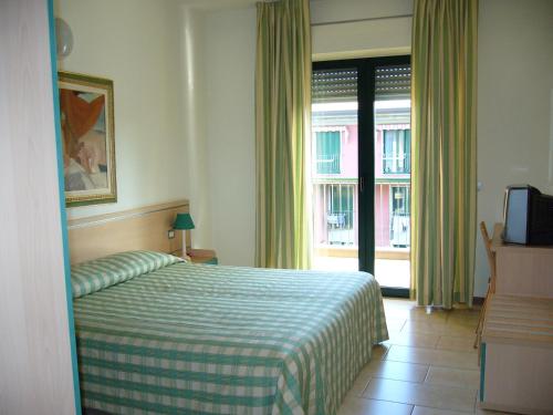 a bedroom with a bed with a green and white blanket at Residence Spiaggia D'Oro in Desenzano del Garda
