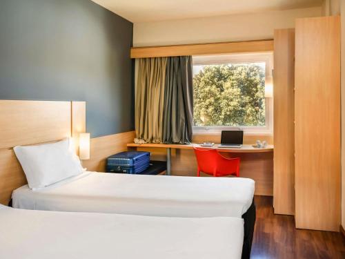 um quarto de hotel com 2 camas e uma secretária com um computador portátil em ibis Paulinia em Paulínia