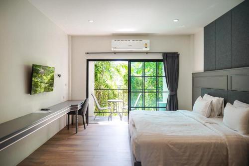a bedroom with a bed and a desk and a window at Trat Tara Boutique Hotel in Ban Sa Sisiat