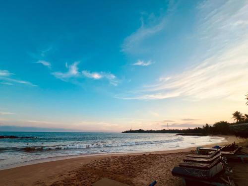 einen Strand mit einer Gruppe von Stühlen und dem Meer in der Unterkunft Opera Tangalle in Tangalle