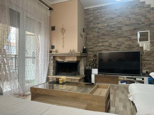 a living room with a large television and a fireplace at JD Maisonette for 4 in Neoi Epivates