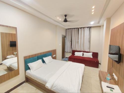 a bedroom with a white bed and a red couch at Hotel Sanskar Palace in Godarpura