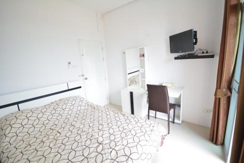a bedroom with a bed and a desk and a television at JC Guesthouse @ Suratthani Airport in Surat Thani
