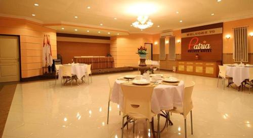 a dining room with white tables and white chairs at Patria Palace Hotel in Blitar