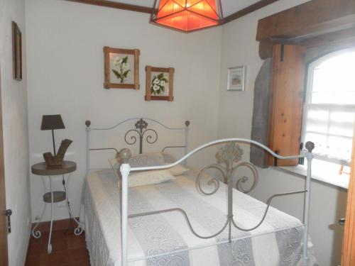 Schlafzimmer mit einem Bett, einem Tisch und einem Fenster in der Unterkunft Casa Ilhéu - Fajã do Fisher in Feteira