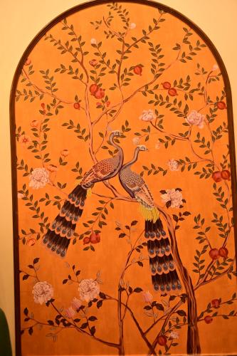 Un cuadro de dos pavos reales en una pared naranja. en Lakshya - The Nature's Farm, en Karungulam