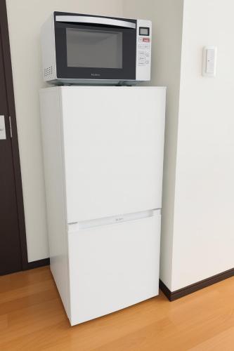 a microwave sitting on top of a white refrigerator at LIO HOTEL Tokyo Nippori in Tokyo