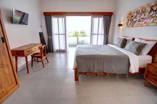 een slaapkamer met een bed, een bureau en een raam bij Casa Serena Cemagi in Canggu