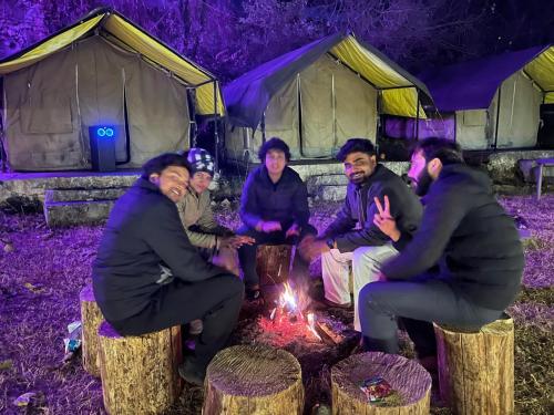 un gruppo di persone seduti intorno al fuoco di fronte alle tende di Royal Mount a Kasol