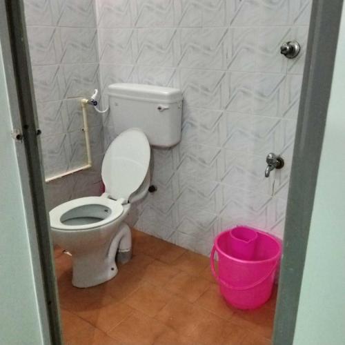 a bathroom with a toilet and a pink bucket at Adb's Srirangam Homes at Gandhi Road in Tiruchirappalli
