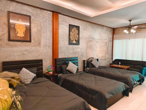 a bedroom with three beds and a couch at Phakphing Erawan Homestay - พักพิง เอราวัณ โฮมสเตย์ in Tha Kradan