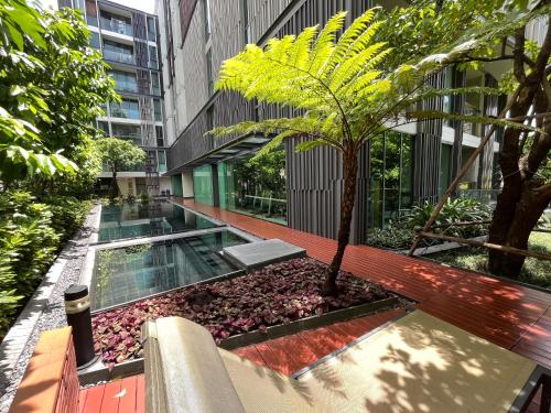 a courtyard with a palm tree in a building at Cozy Spacious 1BR 3pax GardenView, 700m BTS ThongLo, Samitivej, SKV49, Fast wifi in Bangkok