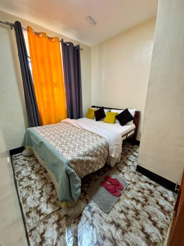 - une petite chambre avec un lit et une paire de chaussures dans l'établissement House of Hera, à Kisumu